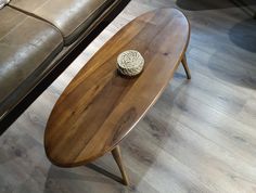 a wooden table with a small round object on it's top next to a couch