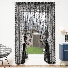 a window with sheer curtains in front of a chair and side table next to it