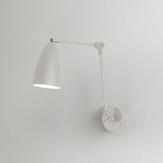 a white wall light mounted on the side of a wall next to a lamp shade