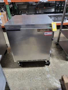 a stainless steel dishwasher sitting on the ground in a warehouse with other items behind it