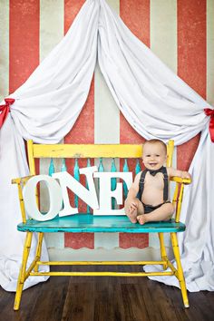 a baby sitting on a bench in front of a one sign