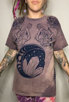 Made To Order  Custom Bleach Dye T Shirt that features a  crescent moon marked with the phases of the moon, crystals front and center accented by butterflies, mushrooms and crystals. On each side of the shirt displays a fern. The image seen is identical front and back.  I carry colors: Black or Navy, Sizes: Small- 4XL! Size chart shown in photos.  100% cotton, safe for fire flow artists. Bleach dyes t-shirts are all hand dyed by me. This is stock photo, due to the creative process of bleach dyei Mushroom And Crystal Shirt, Mystical Cotton Crew Neck T-shirt, Cotton Tops With Moon Print For Festival, Festival T-shirt With Moon Print And Short Sleeves, Festival Graphic Tee With Moon Print, Fairy Grunge Crew Neck T-shirt For Festival, Mystical Short Sleeve Top With Graphic Print, Mystical Graphic Print Short Sleeve Top, Mystical Graphic Print Crew Neck Top