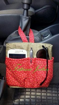 a red purse sitting on top of a car seat next to a cell phone and sunglasses