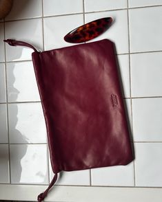 a red leather pouch with a tortoise shell sticking out of it on a white tile floor