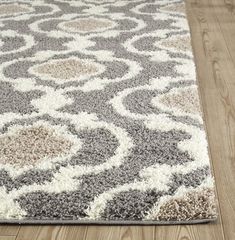 a gray and white area rug on a wooden floor with wood floors in the background