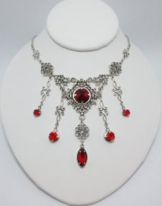 This is a new handmade necklace. It is made with antiqued silver plated filigrees, accented with high quality RUBY RED glass jewels/rhinestones that sparkle like crystals. Decorated portion is 6 1/2" wide and 3 1/4" tall in the center. Necklace is adjustable 15-18" with a lobster clasp and chain extender. If you would like a different length, please send us a message.Matching earrings and headpiece are listed in our store. Medieval Steampunk, Raw Carnelian, Letter Necklace Initials, Steampunk Goth, Antique Silver Necklace, Bridesmaid Necklace Gift, Red Stones, Carnelian Necklace, Vintage Choker