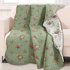 a white couch sitting next to a window covered in a green floral bedspread