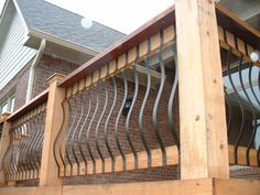 a wooden balcony with metal railings next to a brick house