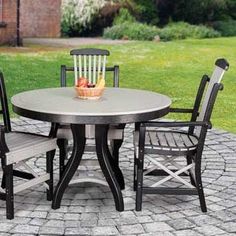 an outdoor table with four chairs and a basket of fruit on it's top