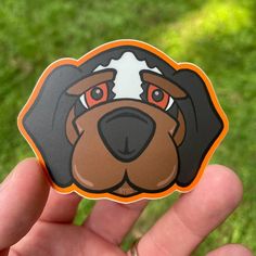 a hand holding a sticker with a dog's face on it