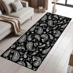 a black and white rug with paisley designs on it in a living room area next to a couch