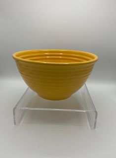 a yellow bowl sitting on top of a clear stand