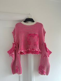 a pink and white striped top hanging on a door