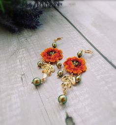 two pairs of earrings with flowers and pearls hanging from them on a white wooden surface