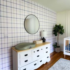 a baby's room with a crib, dresser and mirror on the wall