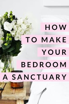 a vase with white flowers sitting on top of a wooden table next to a bed