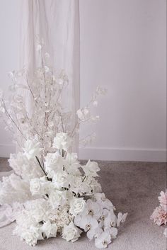 two vases filled with white flowers sitting on the floor