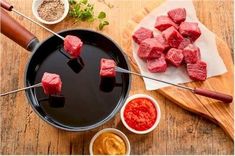 meat on skewers being cooked in a pan with sauces and seasonings