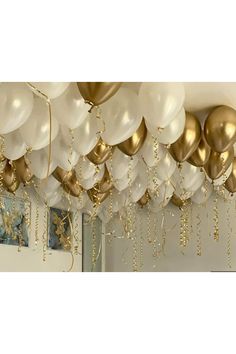 gold and white balloons are hanging from the ceiling