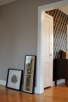 two framed pictures sit on the floor in front of a door with an entry way leading to another room