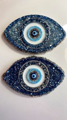 two blue and white plates sitting on top of a table with an evil eye in the center