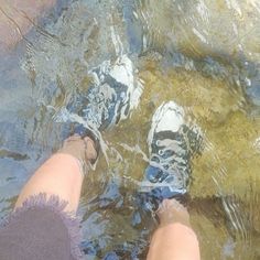 two people standing in the water with their feet up