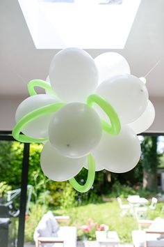 a bunch of balloons are hanging from the ceiling in front of a patio with tables and chairs