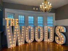 the words the woods are lit up in front of a chandelier and windows