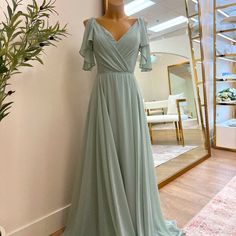 a dress is on display in front of a mirror and a plant next to it