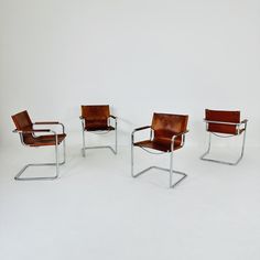 four leather chairs sitting next to each other on a white floor with one chair in the middle