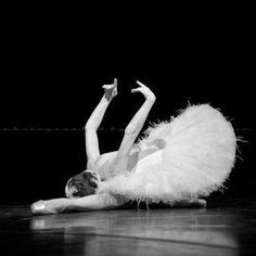 a ballerina is laying on the floor with her arms in the air