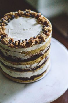 there is a cake with white frosting and chocolate chips on top, sitting on a plate