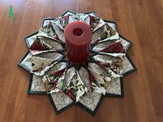 a red candle sitting on top of a table next to a quilted doily