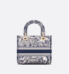 The Lady D-Lite bag combines classic elegance with House modernity. The style is fully embroidered with the blue Toile de Jouy motif. The front features a Christian Dior Paris signature while the thick D.I.O.R. charms in pale gold-finish metal enhance the silhouette. Equipped with a wide, reversible and removable embroidered shoulder strap, the medium Lady D-Lite bag can be carried by hand or worn crossbody.. Luxury Tote Bag With Embroidered Logo, Luxury Double Handle Shoulder Bag With Embroidered Logo, Luxury Shoulder Bag With Embroidered Logo And Top Handle, Designer Embroidered Bags For Daily Use, Luxury Shoulder Bag With Embroidered Logo For Daily Use, Luxury Bags With Embroidered Logo For Daily Use, Elegant Top Handle Shoulder Bag With Embroidered Logo, Luxury Embroidered Top Handle Shoulder Bag, Designer Embroidered Tote Bag