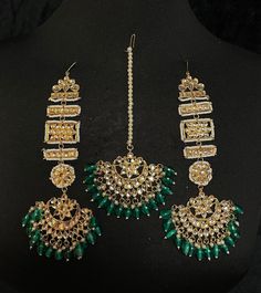 Indian Wedding Mehendi jewelry - Emerald Green Indian Maang passa with jhumka earring with ear climber variation This kundan tikka set is elaborated with precious emerald gem drops. This beautiful mang passa set comes with matching embellished gold-plated earrings climber with green drops.  This rare-find mang passa set is handcrafted with clear Kundan gems on the asymmetrically plated ear climber. Gold plated tikka set is further ornated with luxurious pearl drops. It is the jewelry set sure to Luxury Green Chandbalis With Tilla, Green Bollywood Tikka With Intricate Design, Green Intricate Design Tikka For Festivals, Traditional Green Heavy Tikka, Handmade Gold Kundan Tikka, Green Bollywood Jhumkas For Ceremonial Occasions, Green Tilla Tikka For Ceremonial Occasion, Green Stone Work Tikka For Ceremonial Occasions, Green Tilla Jhumkas For Ceremonial Occasions