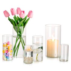 a vase filled with lots of pink tulips next to candles and candies