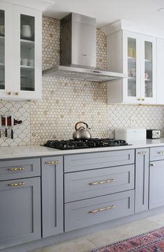 a kitchen with gray cabinets and gold trimmings on the backsplashes