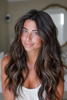 Smiling woman with long, wavy dark hair wearing a white top indoors. Winter Hairstyles Dark Hair, Highlights On Cool Brown Hair, Black Hair With Blonde And Caramel Highlights, Dark Hair With Framing Highlights, Caramel Brown Hair On Brown Skin, Lowlight Hair Color Dark Brown, Dark Hair Some Highlights, Dark Brown Hair With Layers And Highlights, Dimensional Caramel Highlights