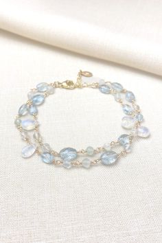 This bracelet showcases delicate moss aquamarine gemstones paired with radiant rainbow moonstones, creating a lovely, feminine style. The artisan meticulously hand-wire-wraps each gemstone bead, creating a beautiful, double-layered chain.  The lobster claw clasp and extender chain allow for an adjustable fit. Bracelet length:  7 inches plus 1-inch extender chain MATERIALS ~ Aquamarine ~ Rainbow moonstone ~ Gold fill GIFTING ~ Jewelry gift box included. ~ I am happy to ship directly to the recipient.  Enter their address during checkout. ~ If you would like a gift note included in the package, please leave the text of the note in the "Add a note to Marsh Creek Jewelry" message box at checkout. FREE SHIPPING ~ Orders ship within 2 business days. ~ Free shipping is First Class ~ Priority Mail Crystal Bead Jewelry, Moss Aquamarine, Aquamarine Bracelet, Layered Chain, The Lobster, Moonstone Bracelet, Gemstone Beaded Bracelets, Message Jewelry, Aquamarine Gemstone