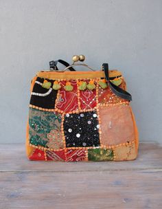 This bag is the real deal, 100% guarantee on many many WOW's! We have made this amazing bag with vintage sari embroidery, embroidered by hand with lots of seed beads and sequins, during the times that there was no TV to keep people occupied. The embroidery is from the far east, Asia. The patches of treasures with smashing colors gives this bag something very exotic. The bag closes with a wonderful brass snap closure (kiss-lock) with a satin finish and stands on it's own. It has leather (upcycled Vintage Embroidered Travel Satchel, Vintage Embroidered Rectangular Satchel, Vintage Embroidered Tote Bag, Vintage Bags For Festivals, Traditional Satchel With Removable Pouch, Vintage Embroidered Bags For Festivals, Vintage Multicolor Embroidered Shoulder Bag, Bohemian Orange Embroidered Bag, Vintage Embroidered Top Handle Bag