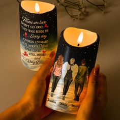 someone holding up two candles that have pictures on them