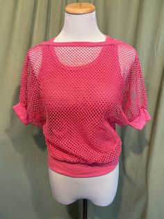 This is a fun vintage top from the 70s or 80s.  Labeled has been snipped out. The bust measures 25" to 34", see measurements below. This fun top has the look of 2 layered tops but is all in one. It is a pink cotton blend strappy, sleeveless tank top bottom layer with a mesh short sleeve top layer. The two layers are attached at the band bottom. The tank part is a soft ribbed tank. The mesh is an open weave with dolman sleeves. The sleeves have knit cuff bands, as does the neckline.    The top is in very good condition!  No damage or soil. Super cute!  If you have never worn vintage before, please measure yourself!! Vintage sizes run smaller than today's sizes, know your measurements before buying! Bust measured from side seam to side seam at the underarm: stretches from 12.5" to 17" for a 90s Style Stretch Tops For Spring, Stretch 90s Style Tops For Spring, Stretch 90s Tops For Spring, Stretchy 90s Style Tops For Spring, Retro Fitted Crew Neck Crop Top, Pink Retro Stretch Top, Fitted Retro Crew Neck Crop Top, Pink Stretch Retro Top, Fitted Retro Crop Top With Crew Neck