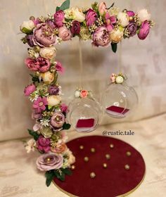 a table topped with two vases filled with flowers and an oval shaped mirror on top of it