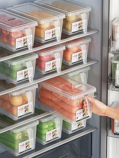 a woman is reaching into an open refrigerator with lots of food in plastic containers on the shelves