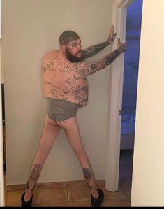 a man with tattoos on his arms and legs is standing in front of a door