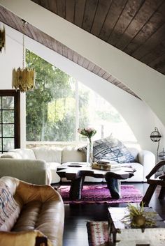 a living room filled with furniture and a large window over the top of it's roof