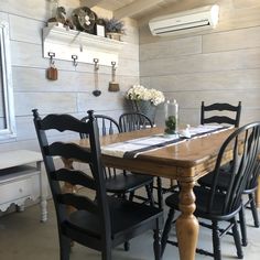 a wooden table with black chairs and white walls