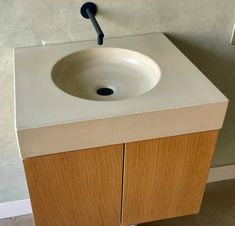 a bathroom sink with a black faucet on the top and wooden cabinets below