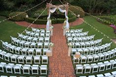 an outdoor ceremony setup with white chairs and string lights