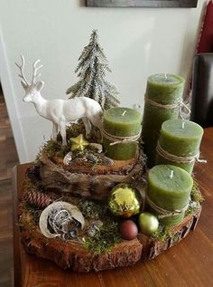 a wooden table topped with candles and christmas decorations next to a deer figurine